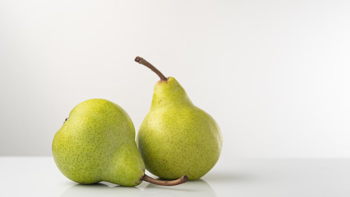 Two ripe green pears on a white background, showcasing fresh produce.